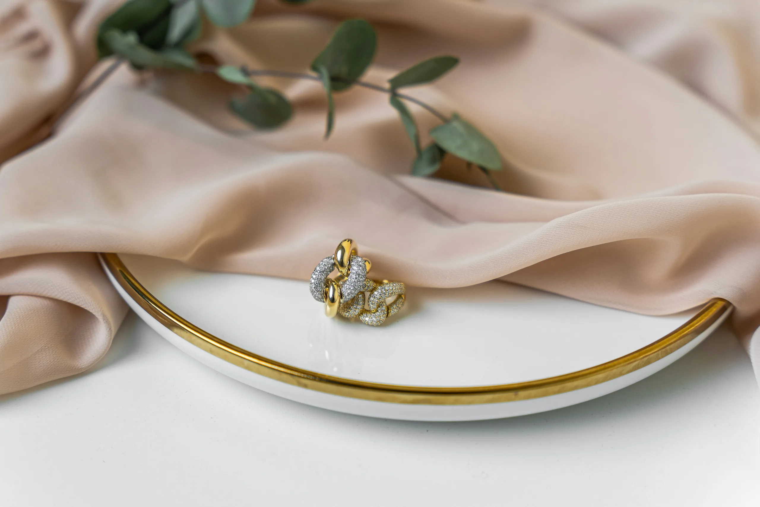 Gold and diamond jewellery arranged on warm silk
