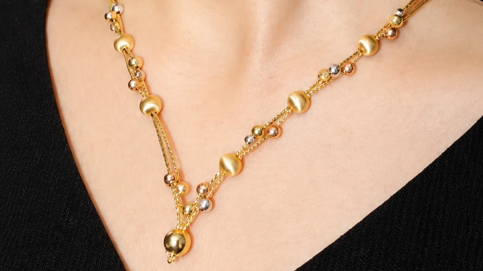 A yellow, white and rose gold necklace worn at the neckline
