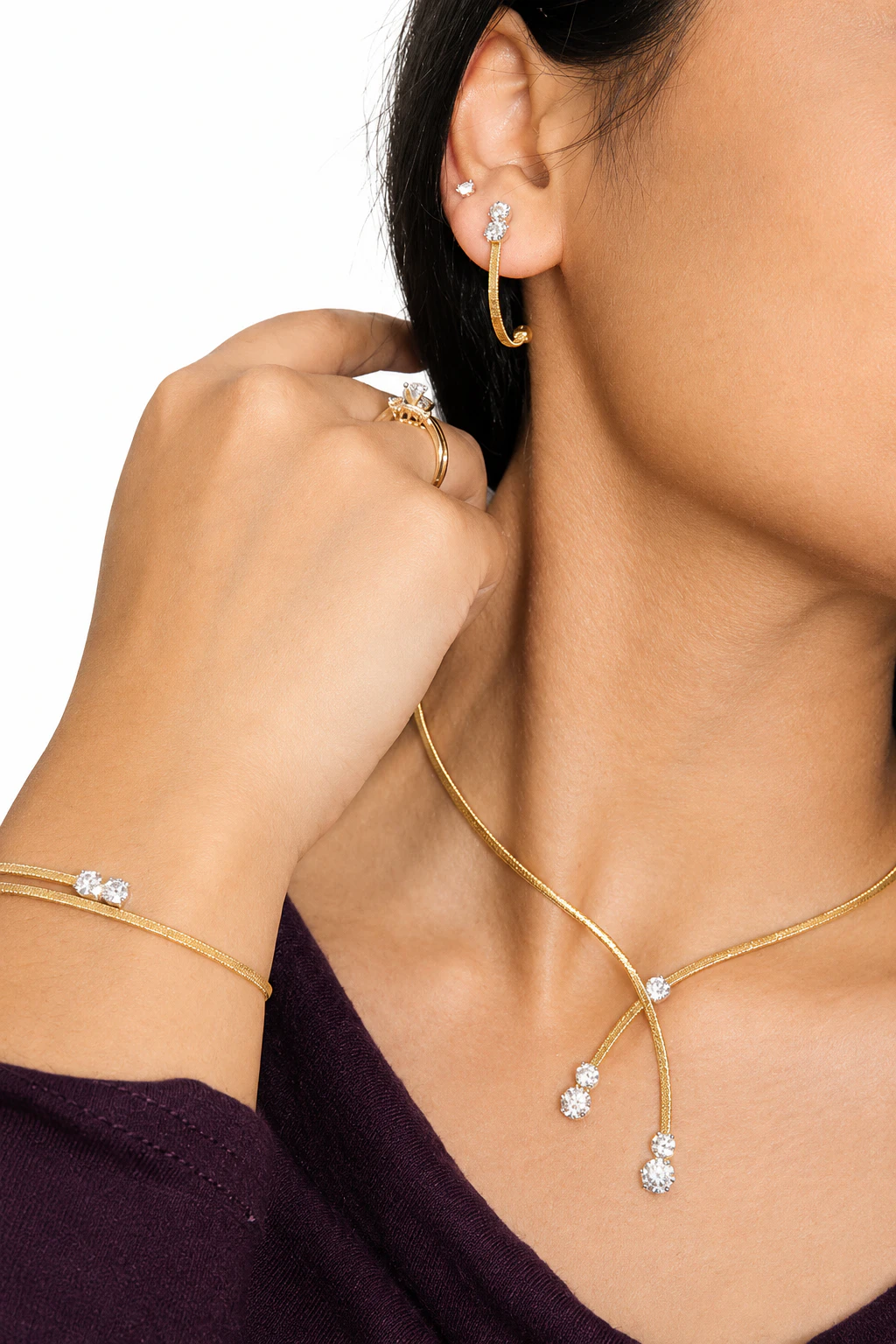 A model wearing delicate yellow gold earrings, necklace, rings and bracelets