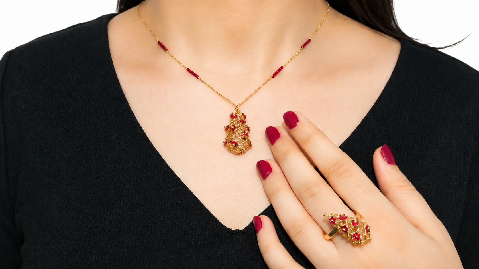 Woman wearing a ruby-detailed gold pendant necklace and matching ring