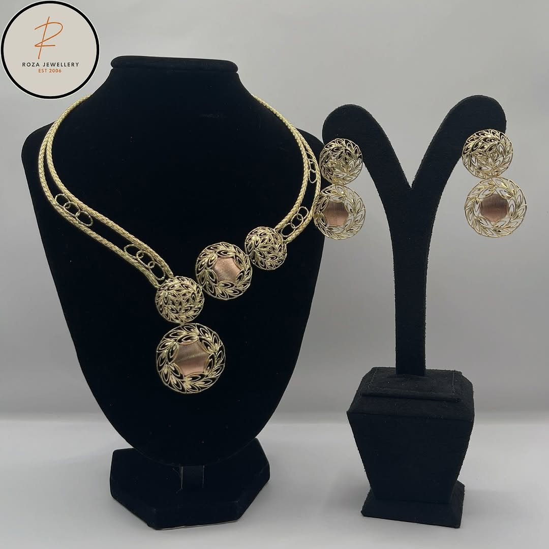 Two-tone filigree necklace and matching drop earrings displayed on black stands