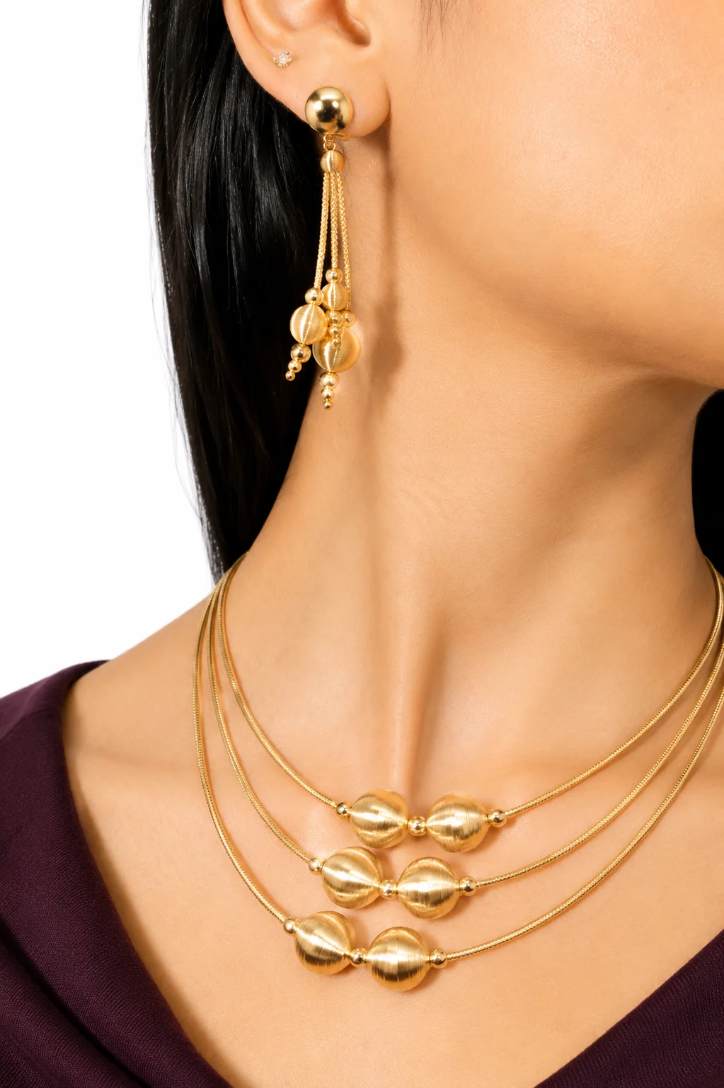 Model wearing gold earrings and a layered gold necklace